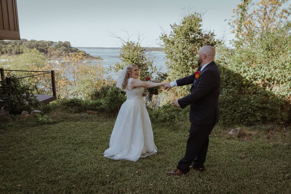 A couple dances together during their outdoor wedding ceremony with water views.