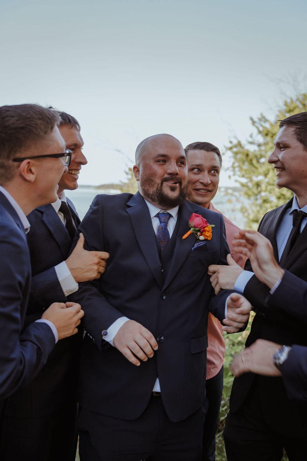 Groomsmen share laughs and jokes during outdoor wedding celebration.