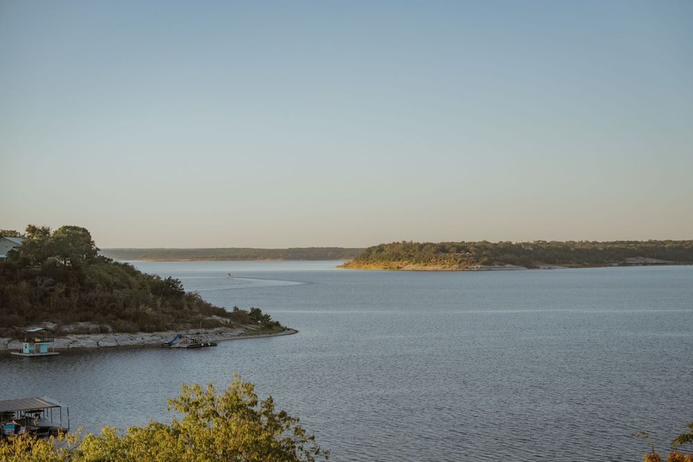 Panoramic view of a serene lake landscape with rocky shoreline under clear blue skies.