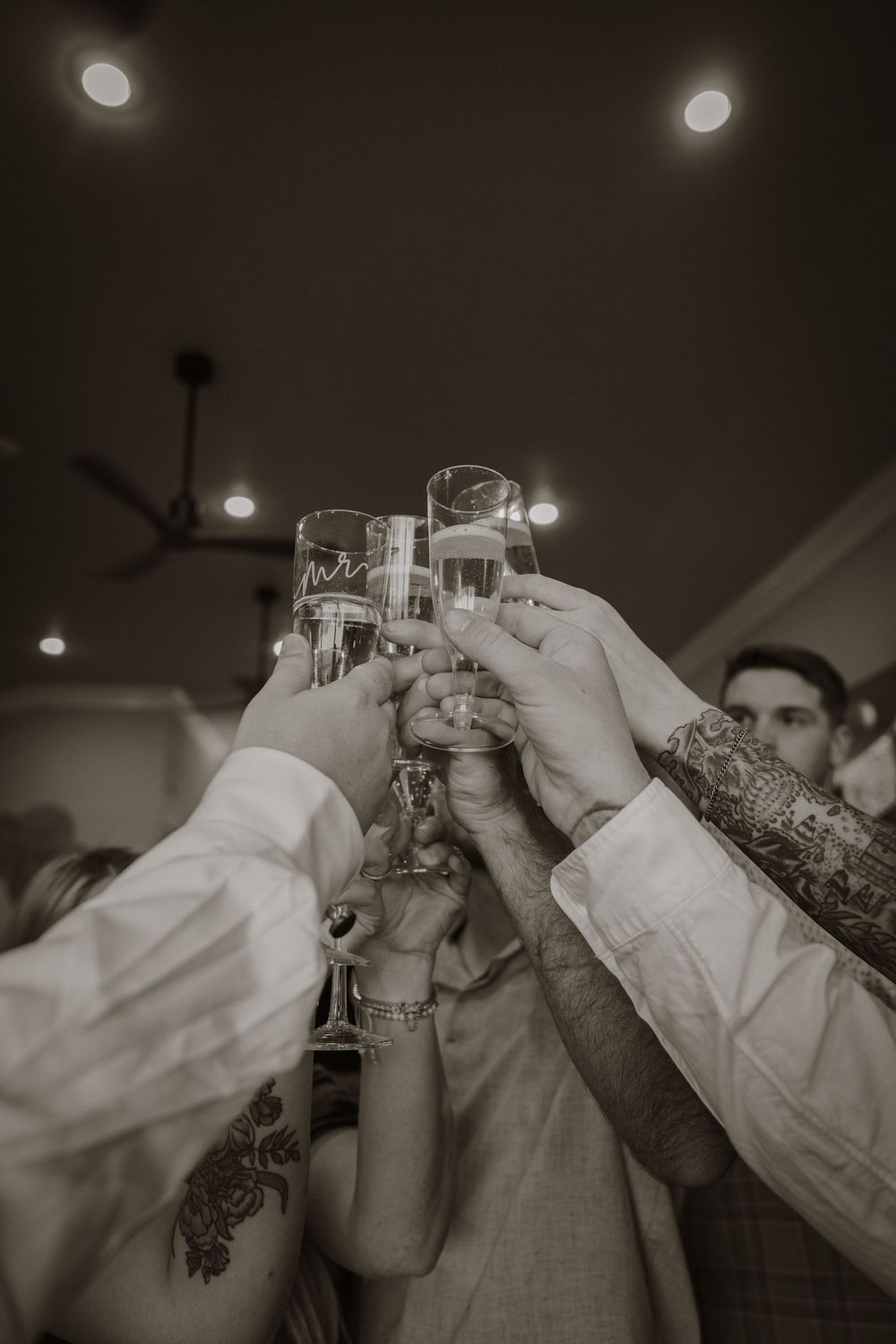 Black and white photo of wedding guests raising glasses in a celebratory toast.