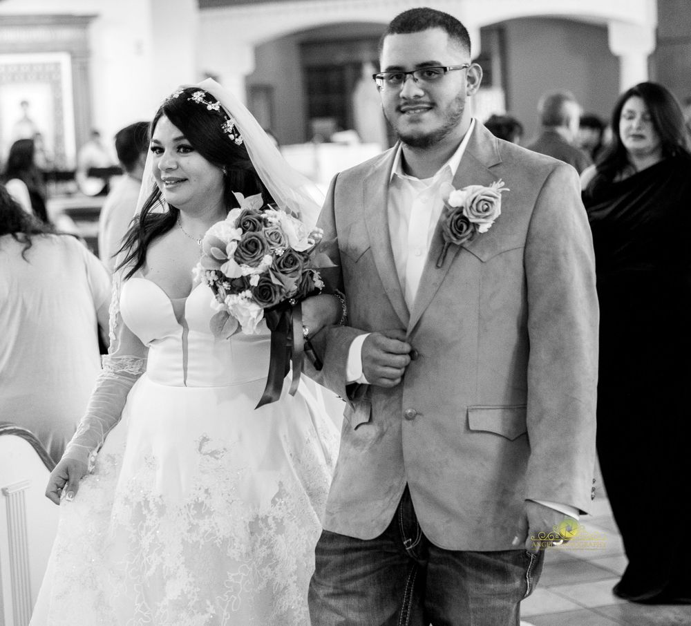 A black and white photo of a wedding couple walking down the church aisle.