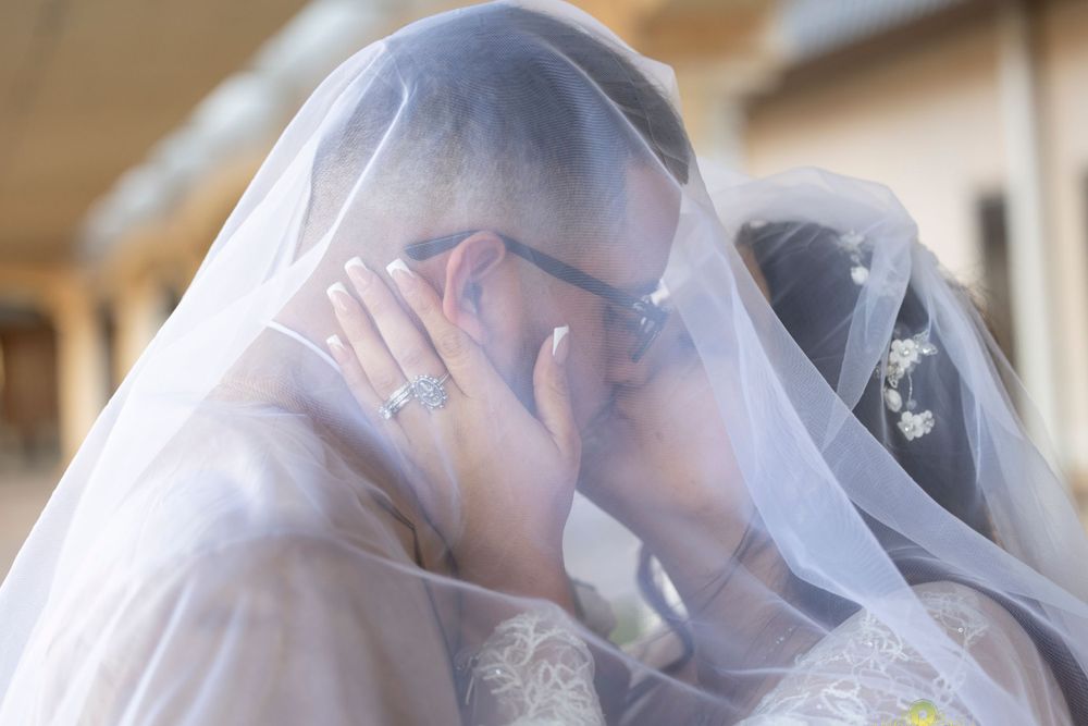Romantic moment between newlyweds under a delicate white veil.