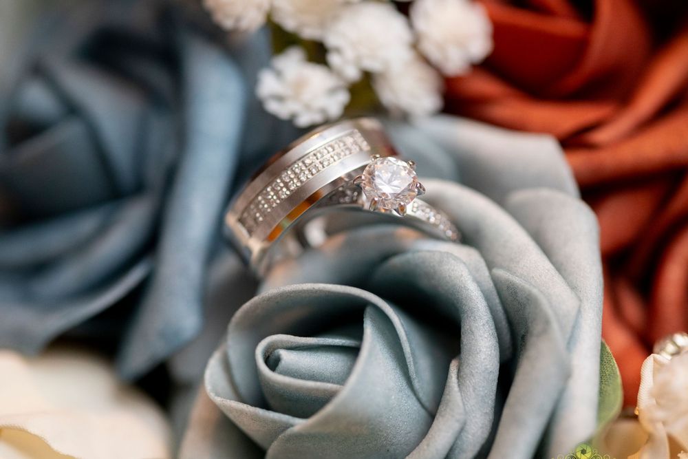 Wedding rings nestled among silk roses in shades of blue and red.