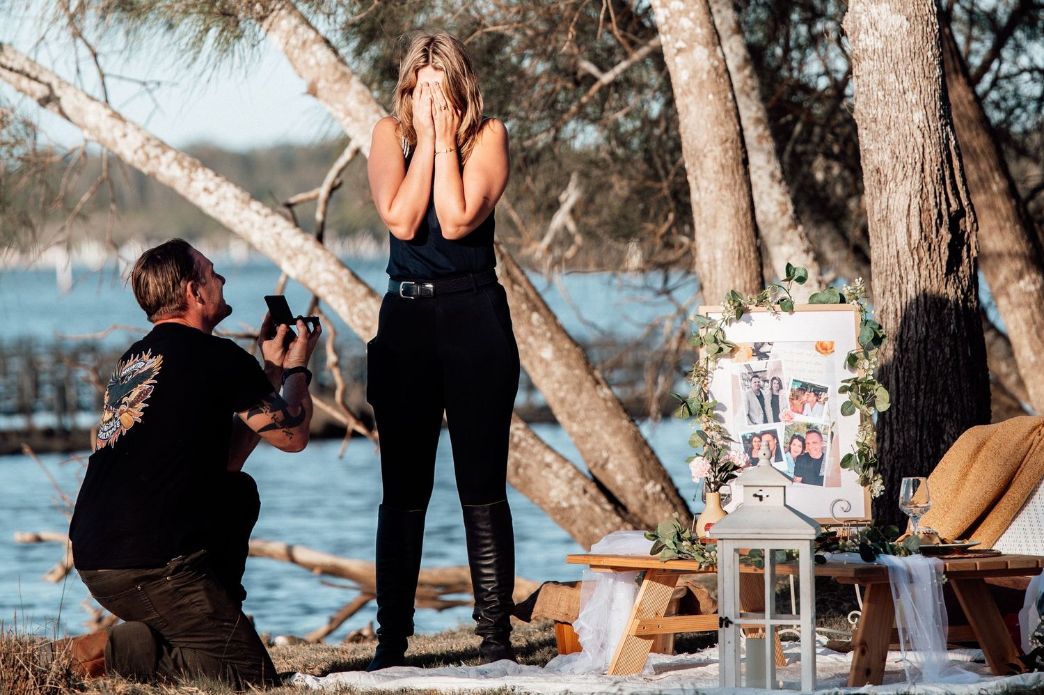 A romantic proposal photoshoot sequence by the water's edge with pine trees in the background at sunset.