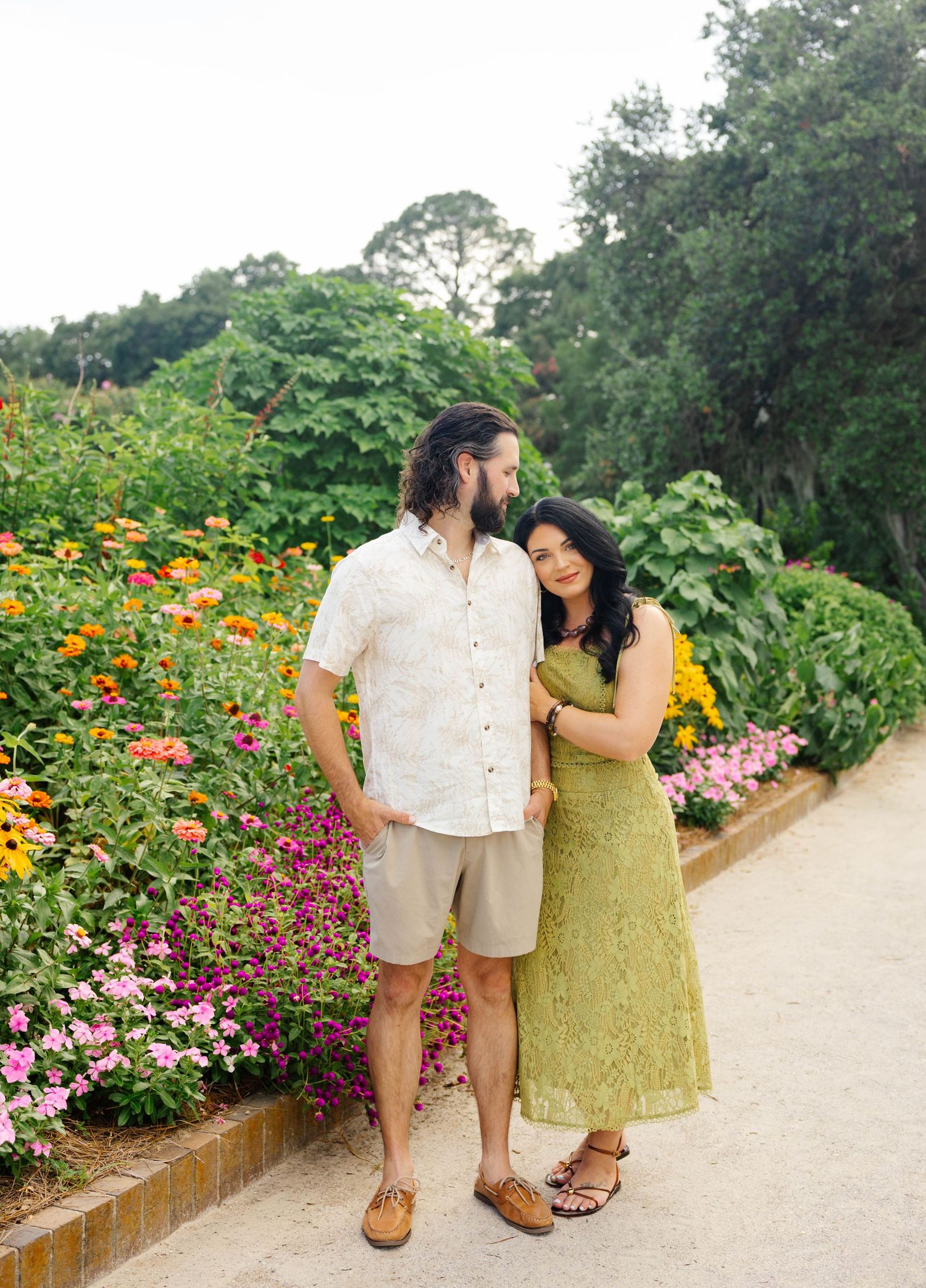 Couple in casual attire sharing romantic moments in a lush green field during golden hour.