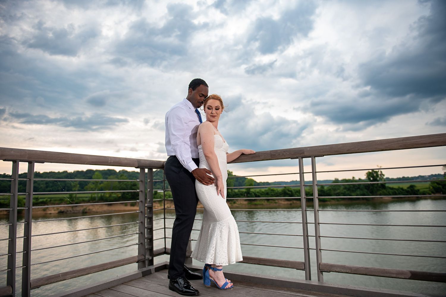 A romantic wedding photo series taken on a dock overlooking a scenic lake and mountains at sunset.