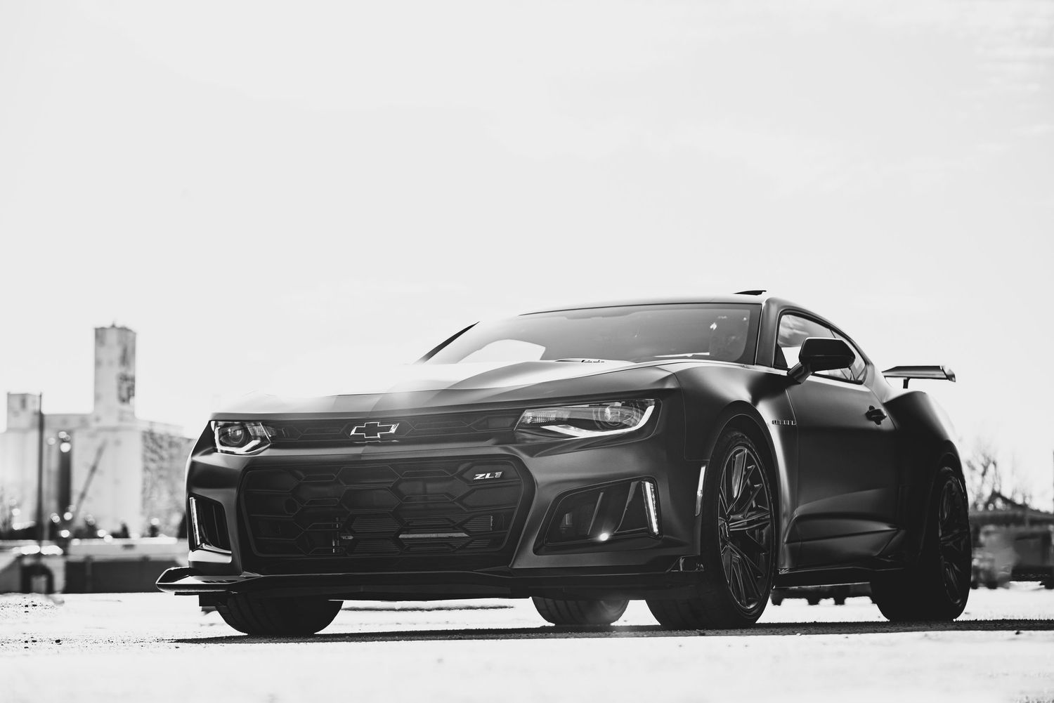 Low angle view of sleek black sports cars lined up in a dramatic monochromatic composition against a light background.