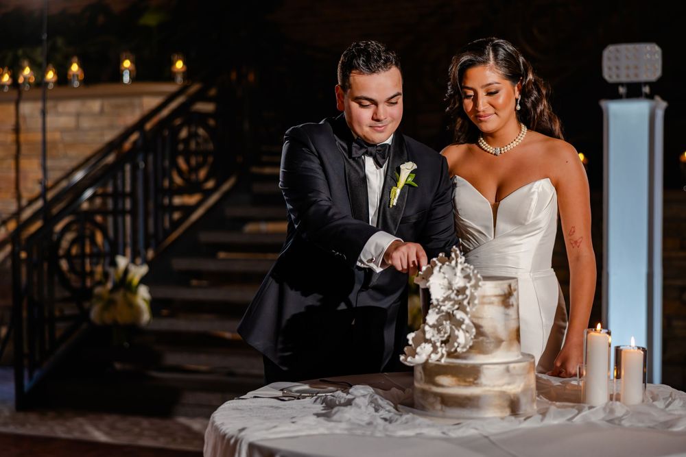 A couple shares a tender moment at their wedding reception while seated at an elegant table with white decor.
