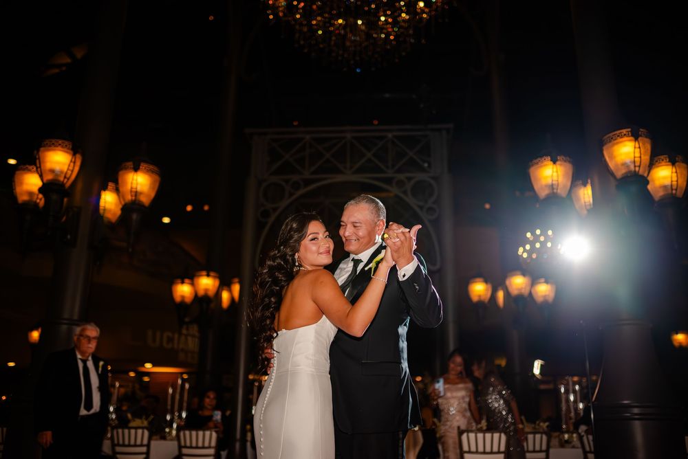 Romantic evening wedding reception with warm amber lighting and elegant table settings creating an intimate atmosphere.