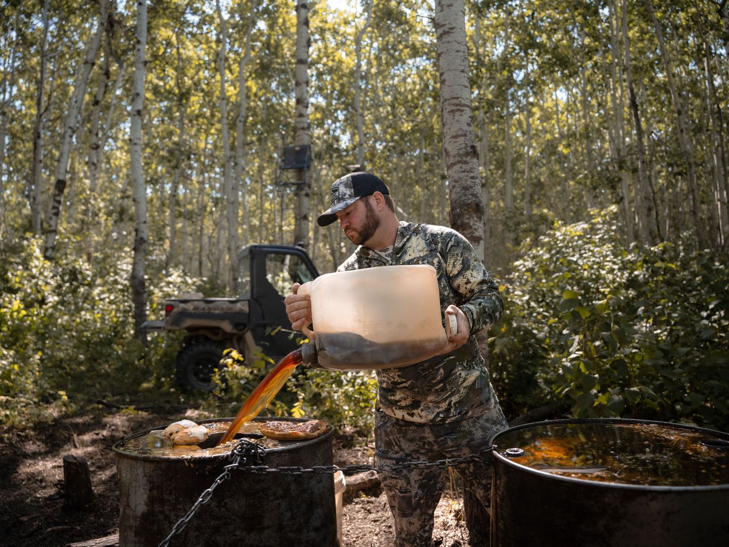 Hunter preparing food in a cast iron pan over a campfire in an aspen forest.