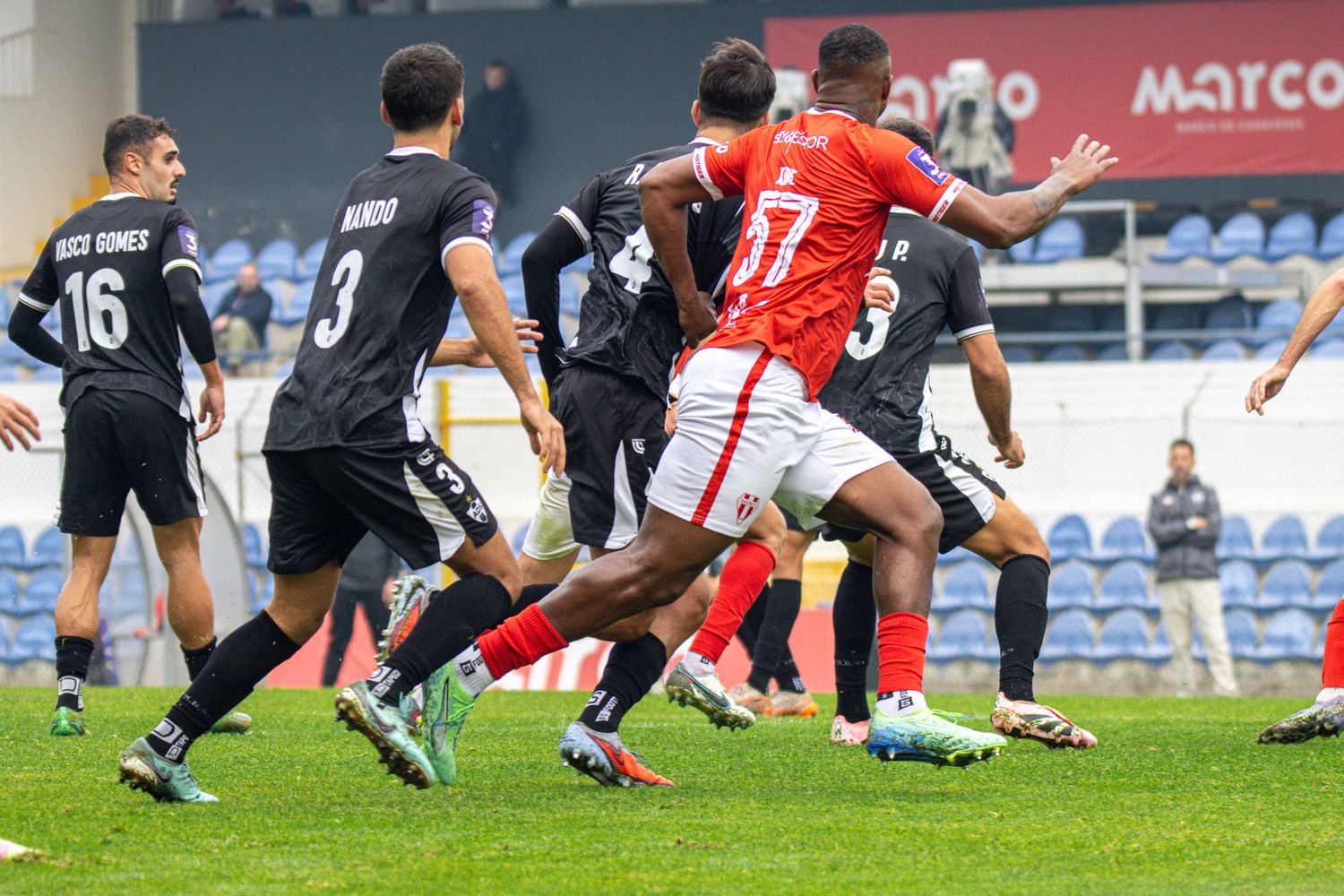 Soccer players in red and black uniforms battle for the ball during a competitive match.