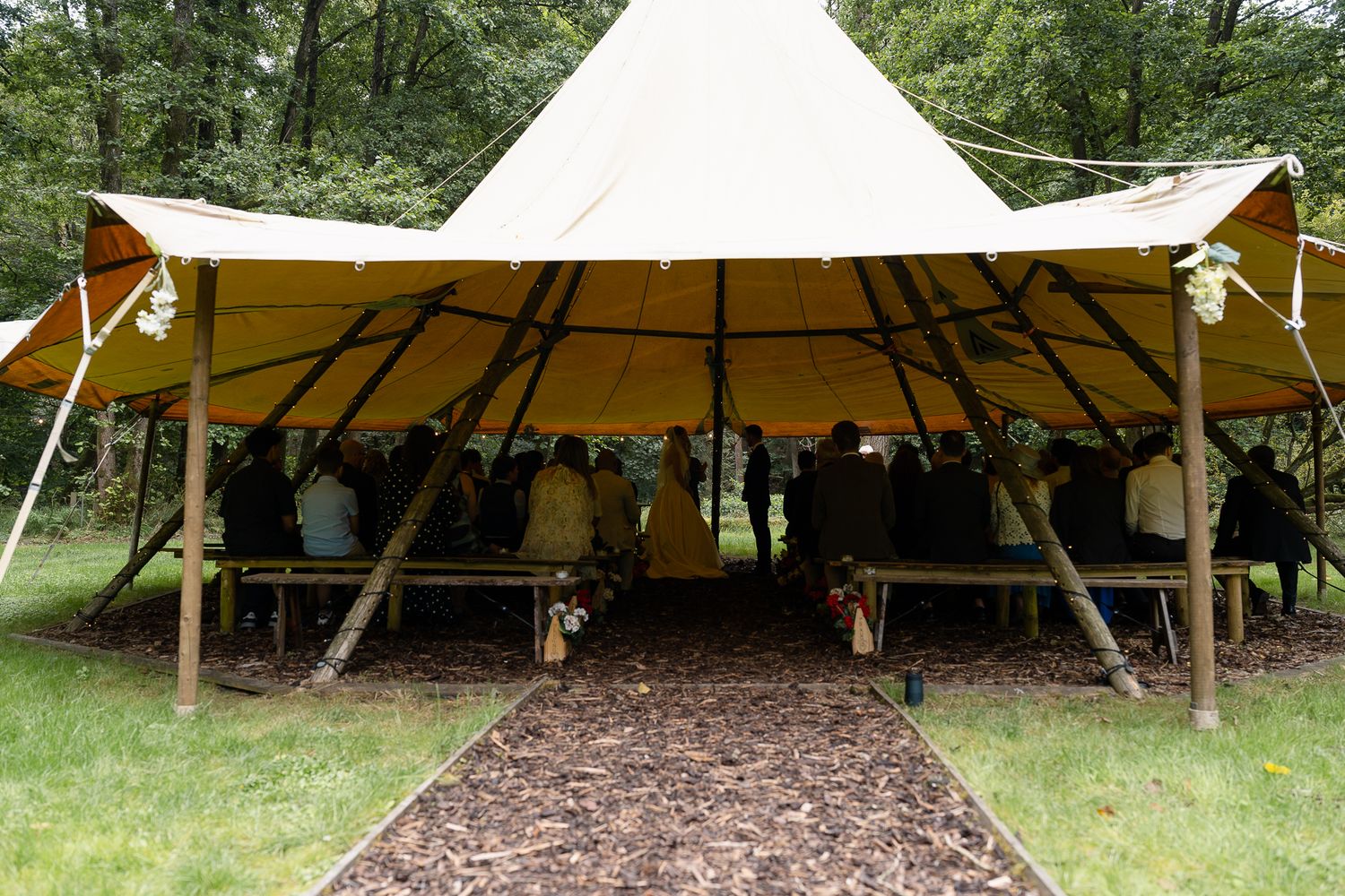 Large white canvas tent structures set up in a wooded outdoor area for an event or gathering.