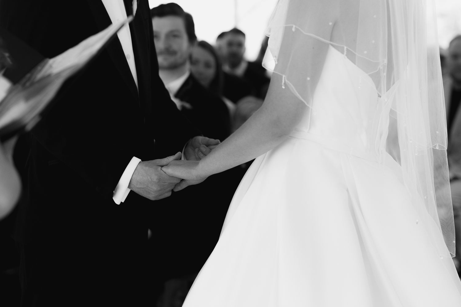 Black and white wedding photo showing a bride and groom embracing during their first dance at a reception.