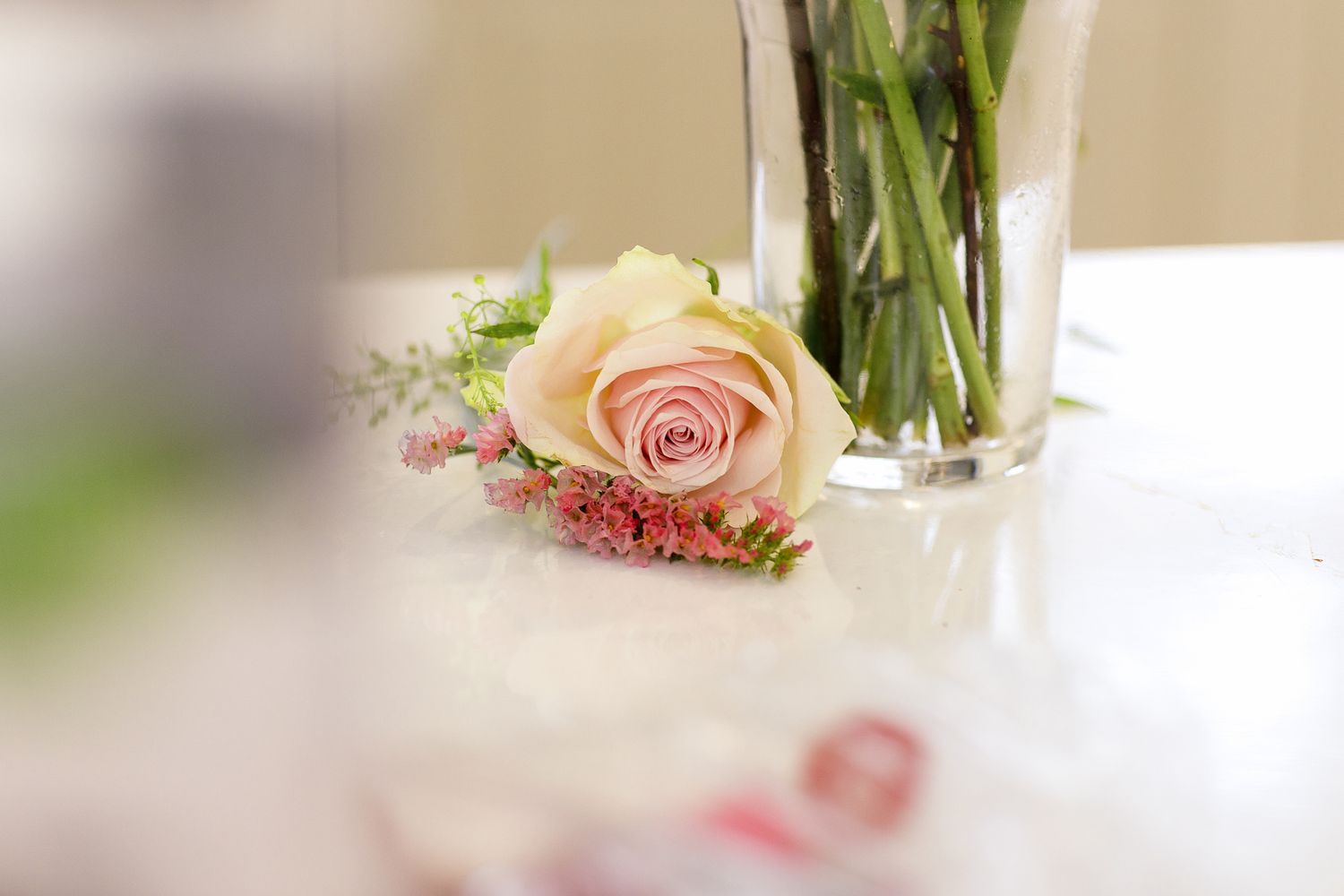 Elegant pink roses and floral centerpieces adorn tables at an indoor event setting.