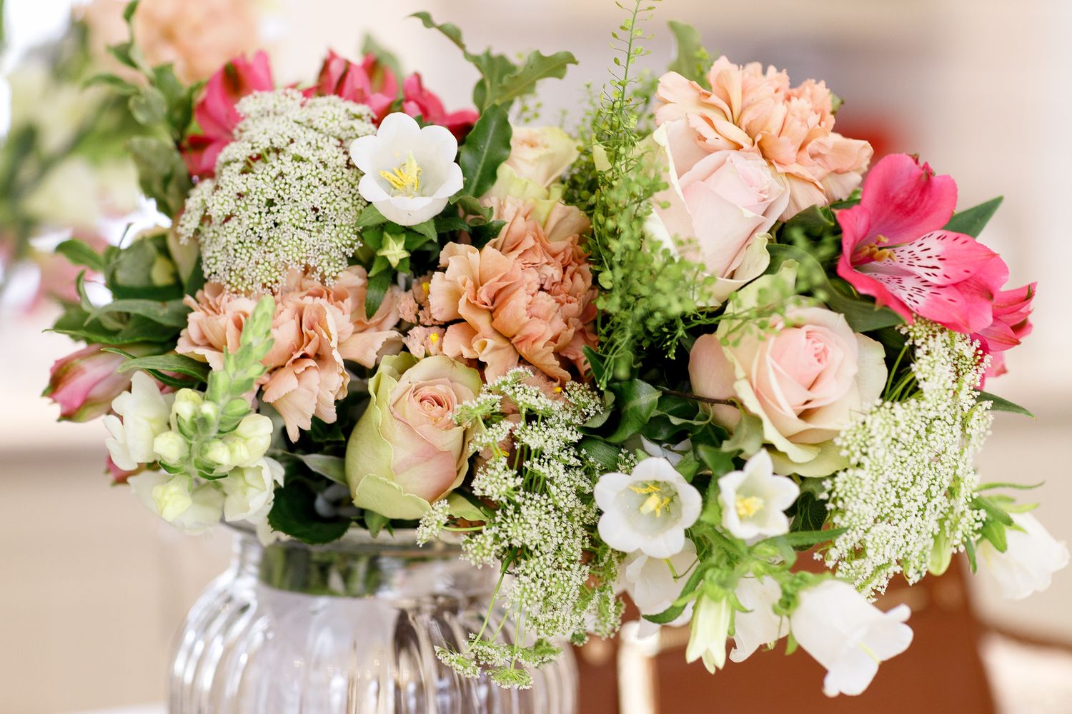 A collection of delicate floral arrangements featuring pink roses, peach blooms, and white flowers in soft, romantic styling.
