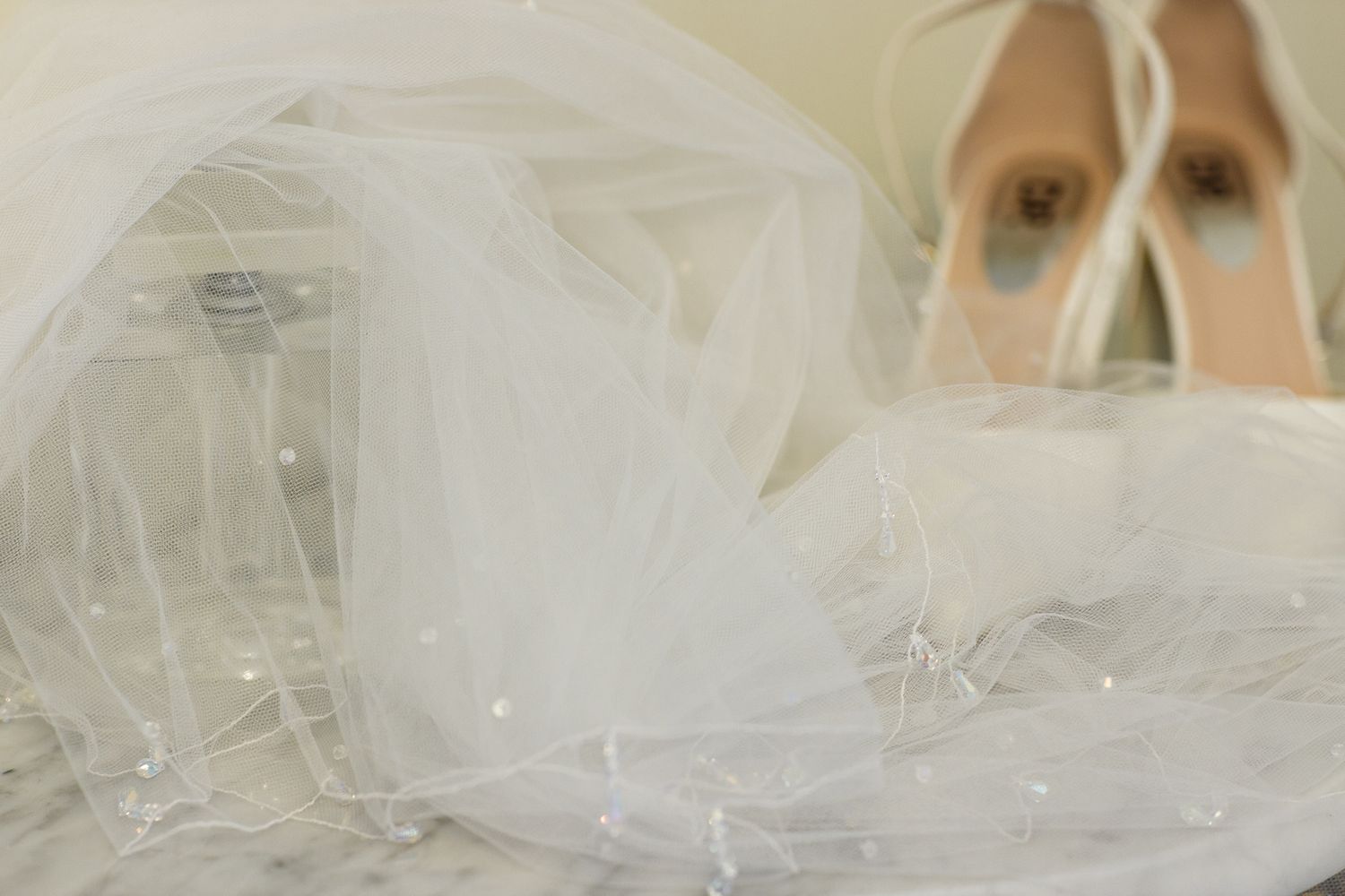 A delicate white wedding veil with intricate lace details flows gracefully in a soft breeze.