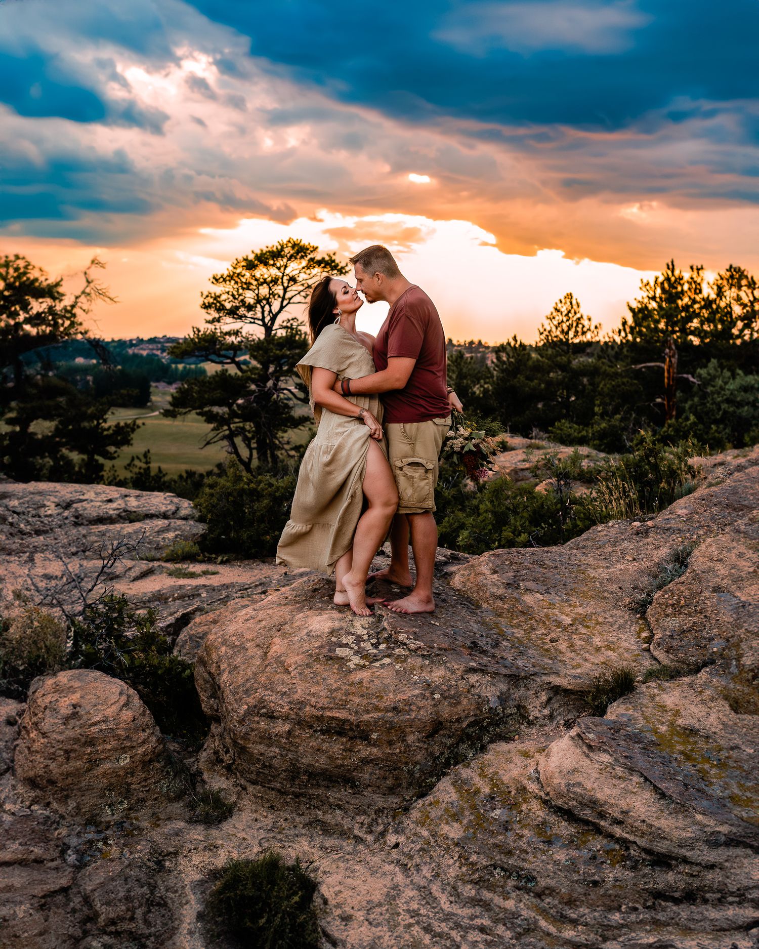 a husband and wife intimately embracing while they kiss from the top of Castlewood canyon state park rock formations.