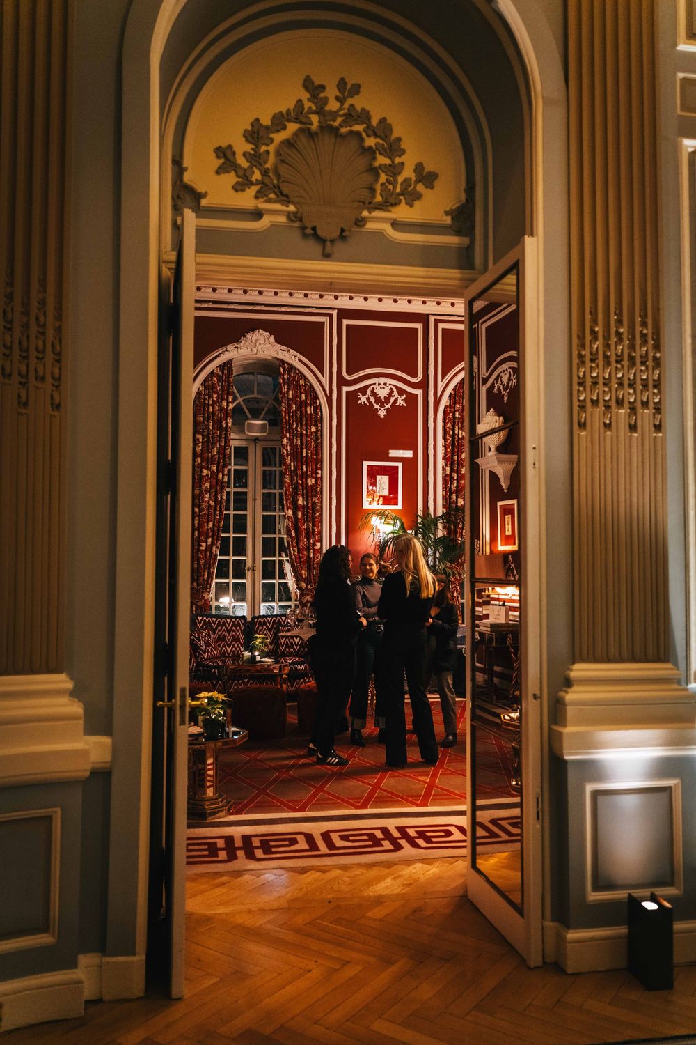Vista del salón durante evento social a través de una puerta con arquitectura clásica