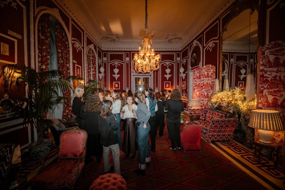 Asistentes conversando durante evento social en salón clásico con decoración elegante