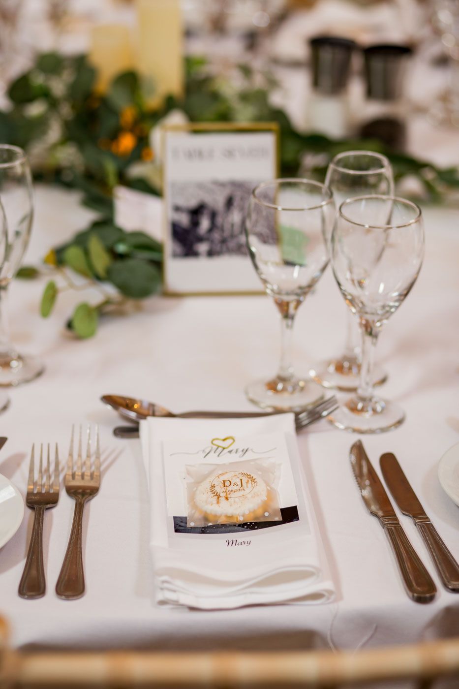 Formal table setting with white linens, wine glasses and gold accents.