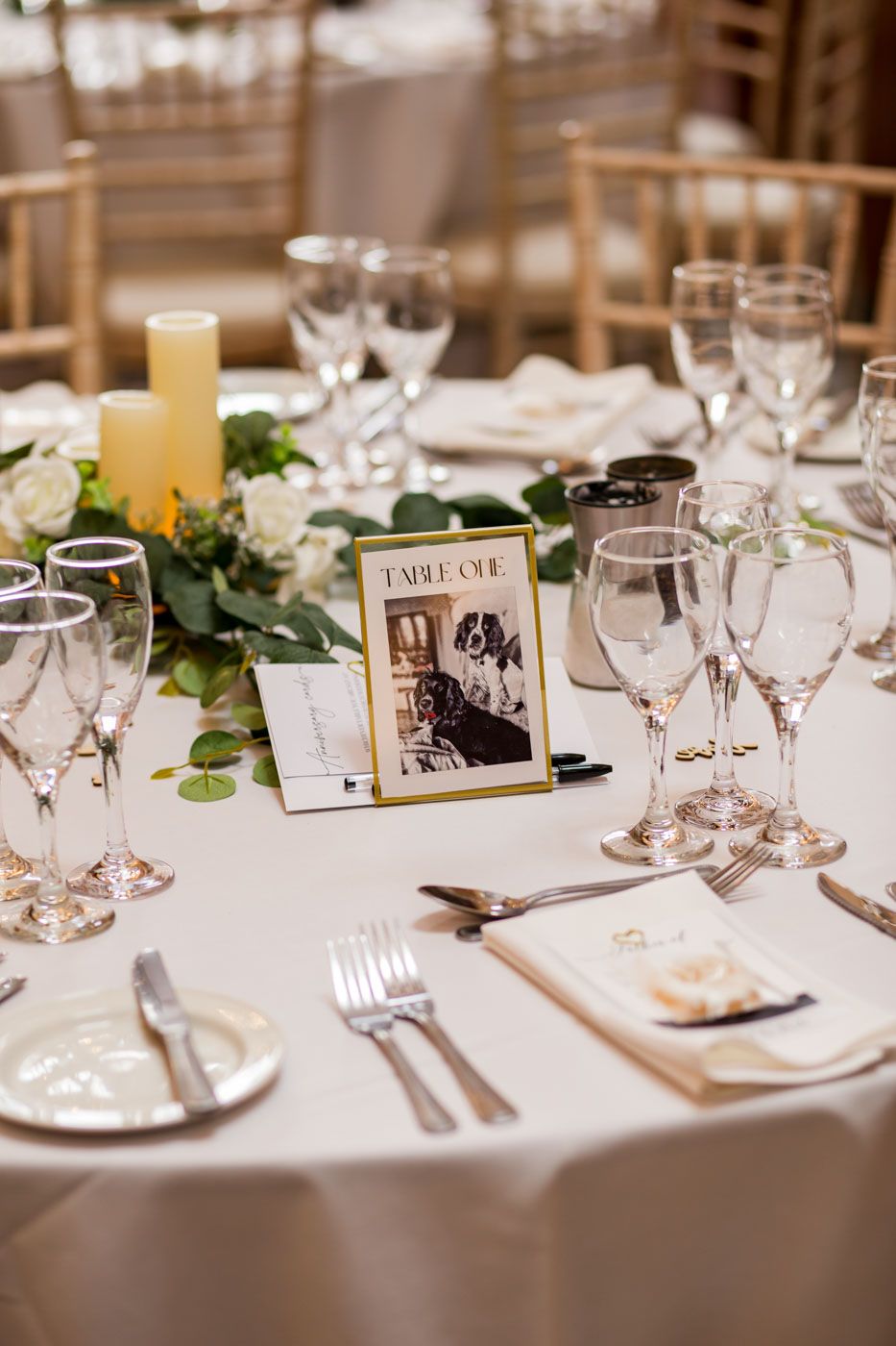 Wedding reception table settings with vintage photos and greenery centerpieces.