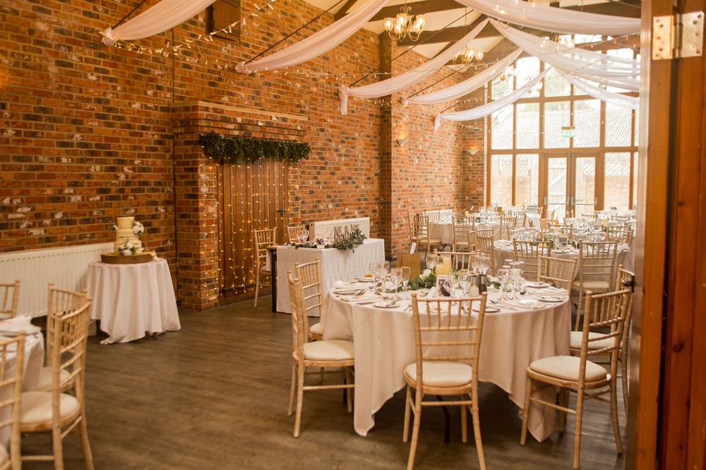 Wedding reception venue with exposed brick walls and elegant white drapery.