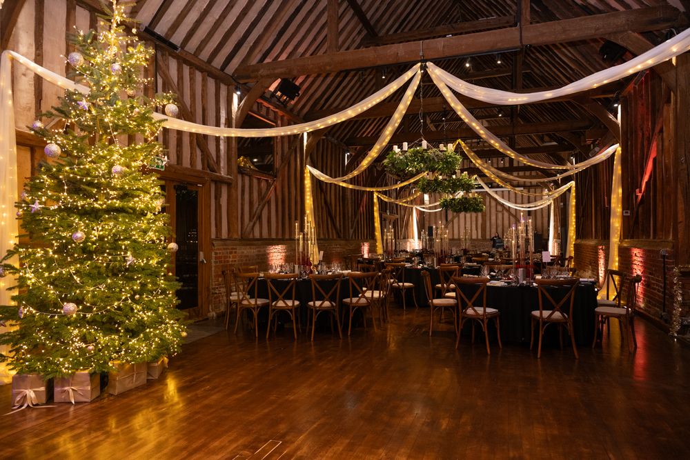 A rustic barn wedding venue decorated with white draping and Christmas trees glowing with warm lights.