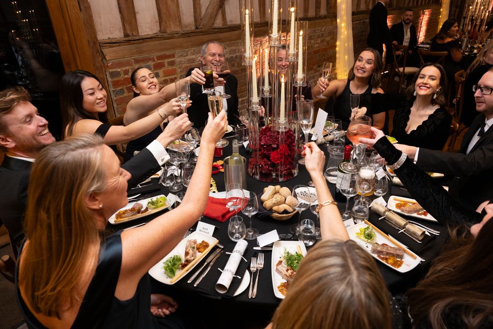 Elegant dinner party guests seated at long tables with candlelight and formal place settings enjoying a special evening.