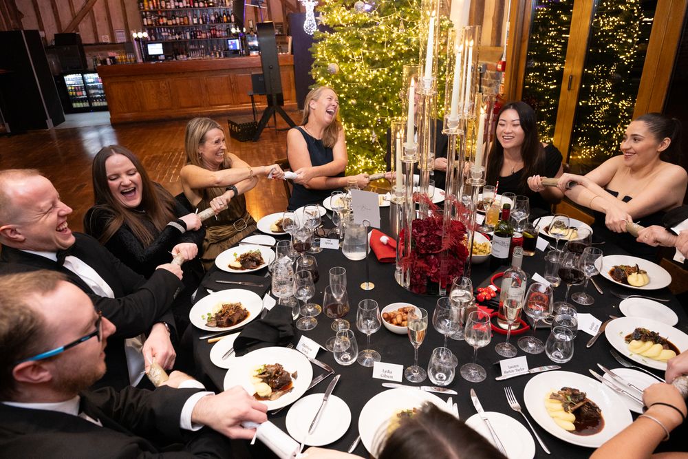 A group of people enjoying dinner and conversation at a restaurant table with plates of food and drinks.