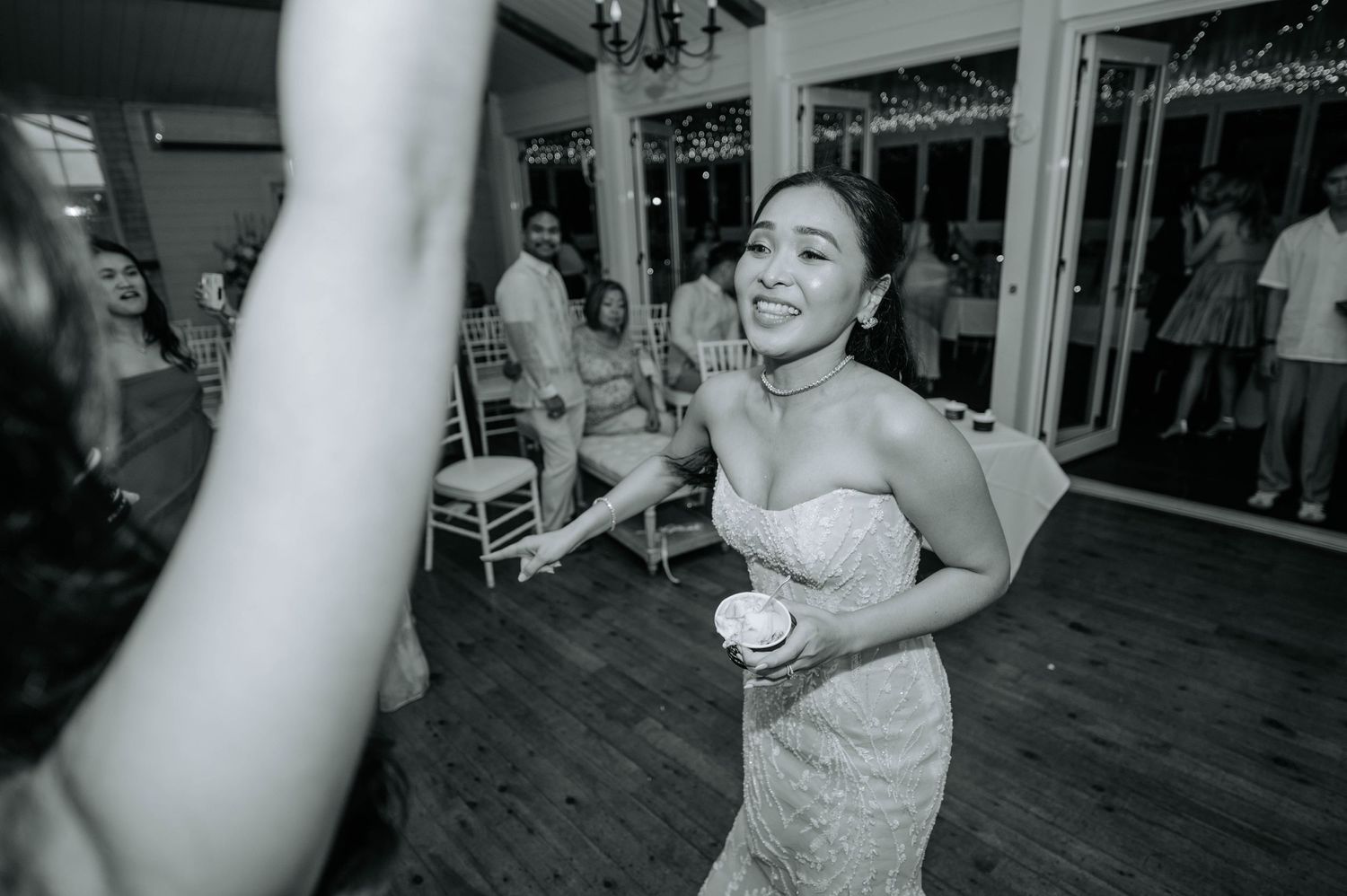 Black and white photo capturing joyful dancing moments during a wedding reception.