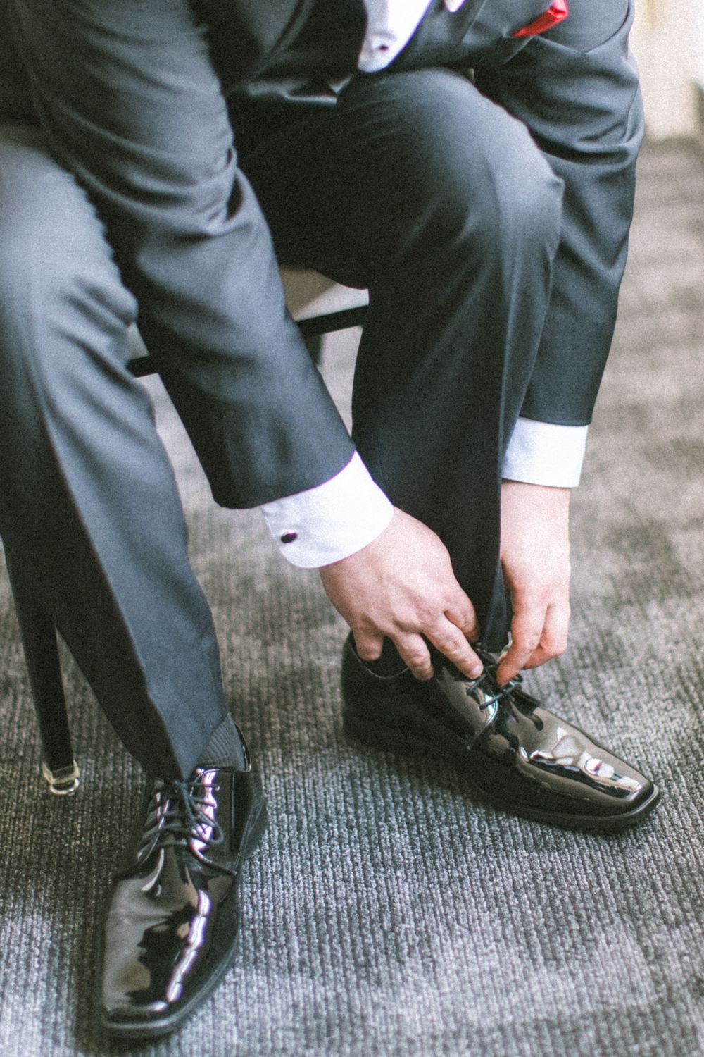 Series of four images showing a person putting on and tying formal black leather dress shoes.