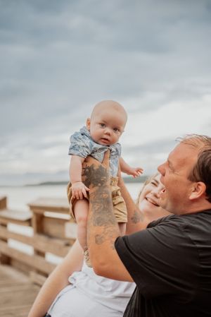 A touching moment shared between parent and infant on a wooden dock by the water.
