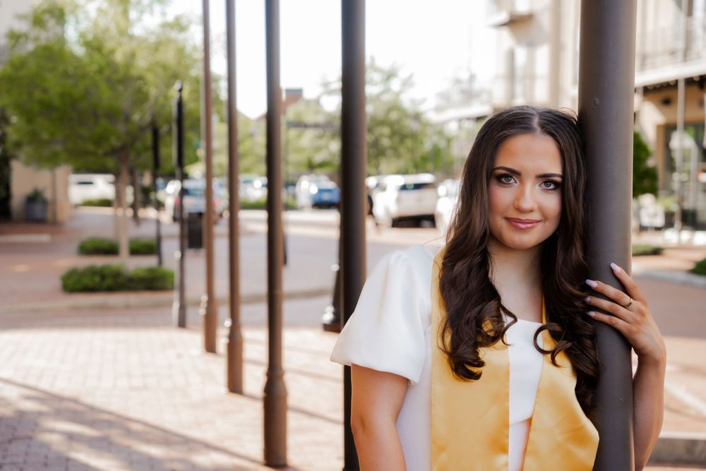 Person in casual attire standing by urban columns on sunny day.