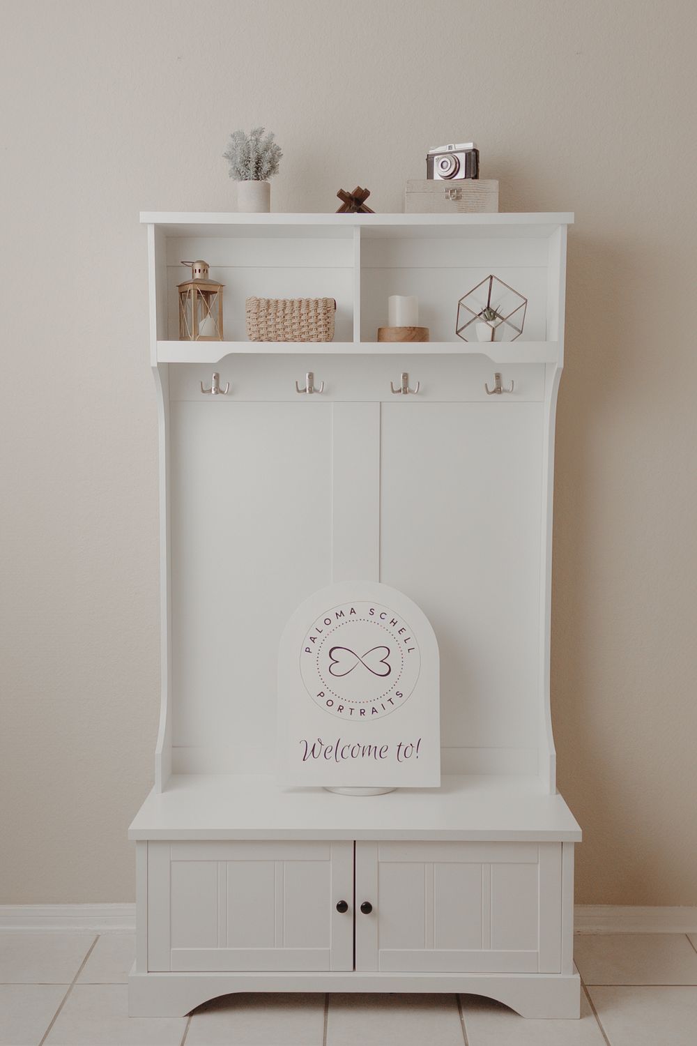 White wooden cabinet storage unit with shelf displaying minimalist home decor items against a neutral wall.