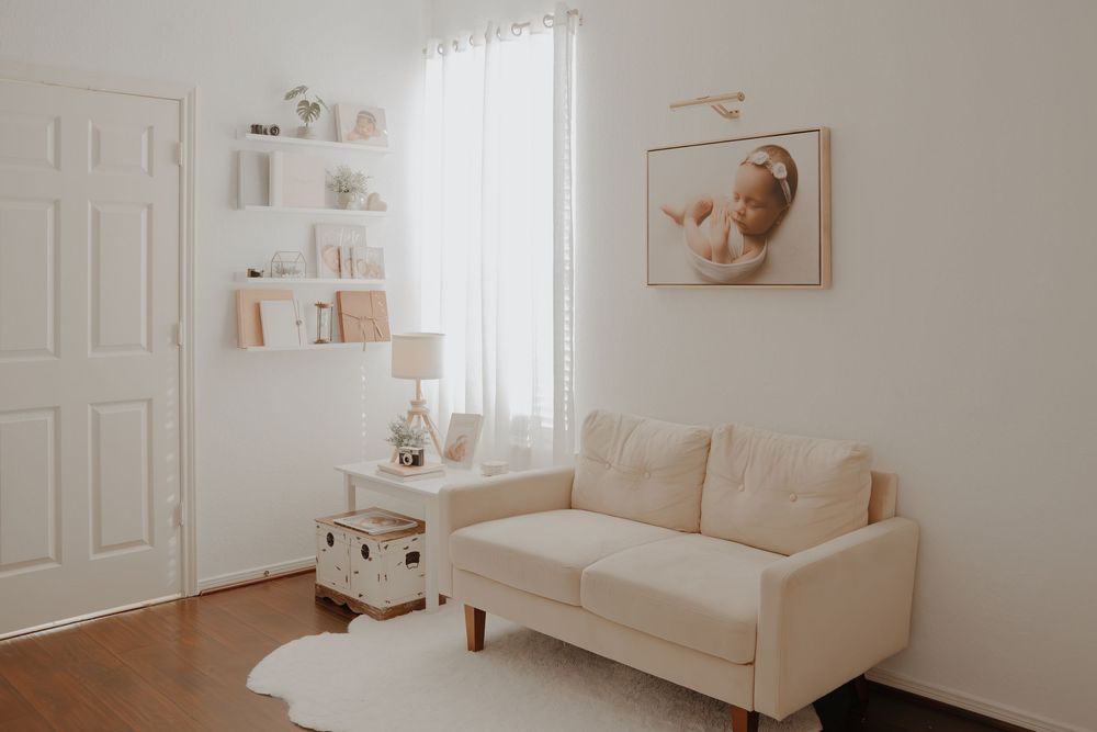 All-white nursery room design featuring white railed cribs, couch, and flowing curtains in a minimalist modern style.