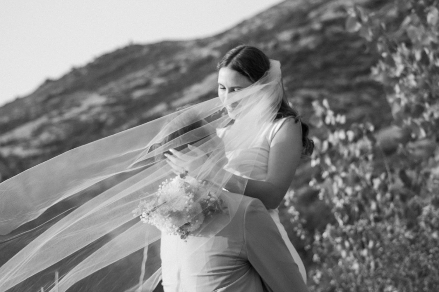 Groom picks up bride in front of Utah mountain landscape.