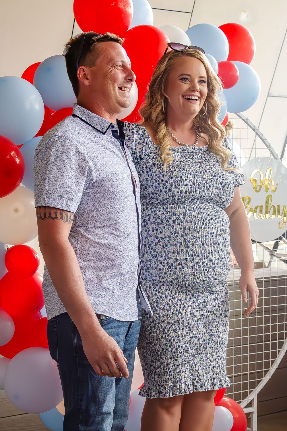 Couple laughing together against backdrop of red, white and blue balloons.