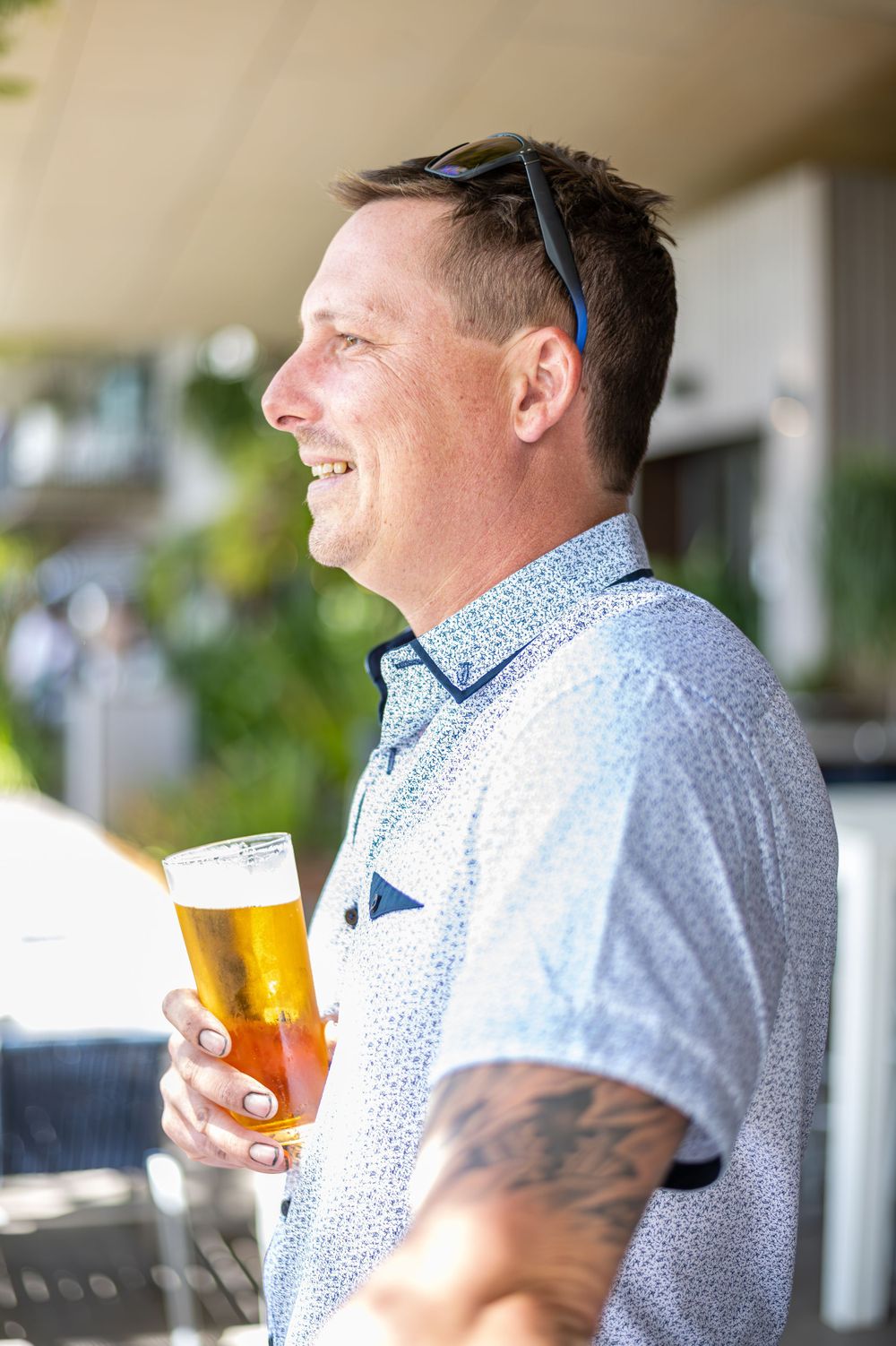 Person enjoying a glass of beer outdoors on sunny day.