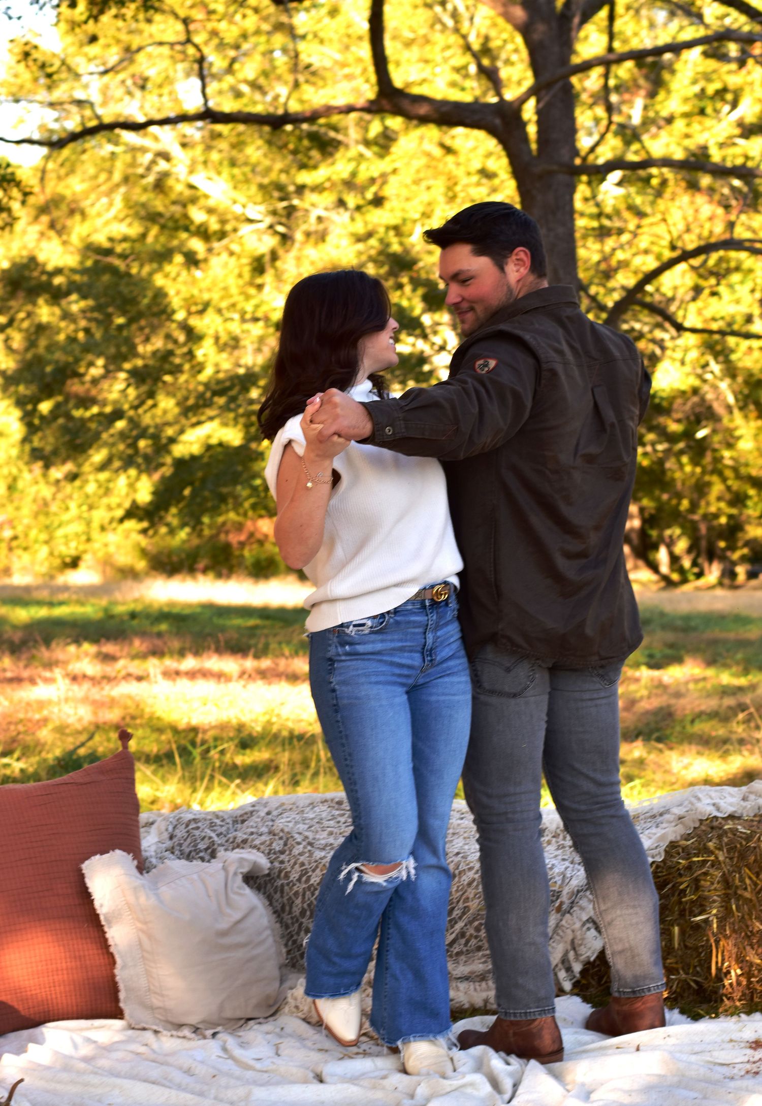 Couple dancing together on a blanket with autumn foliage and pumpkins in background.