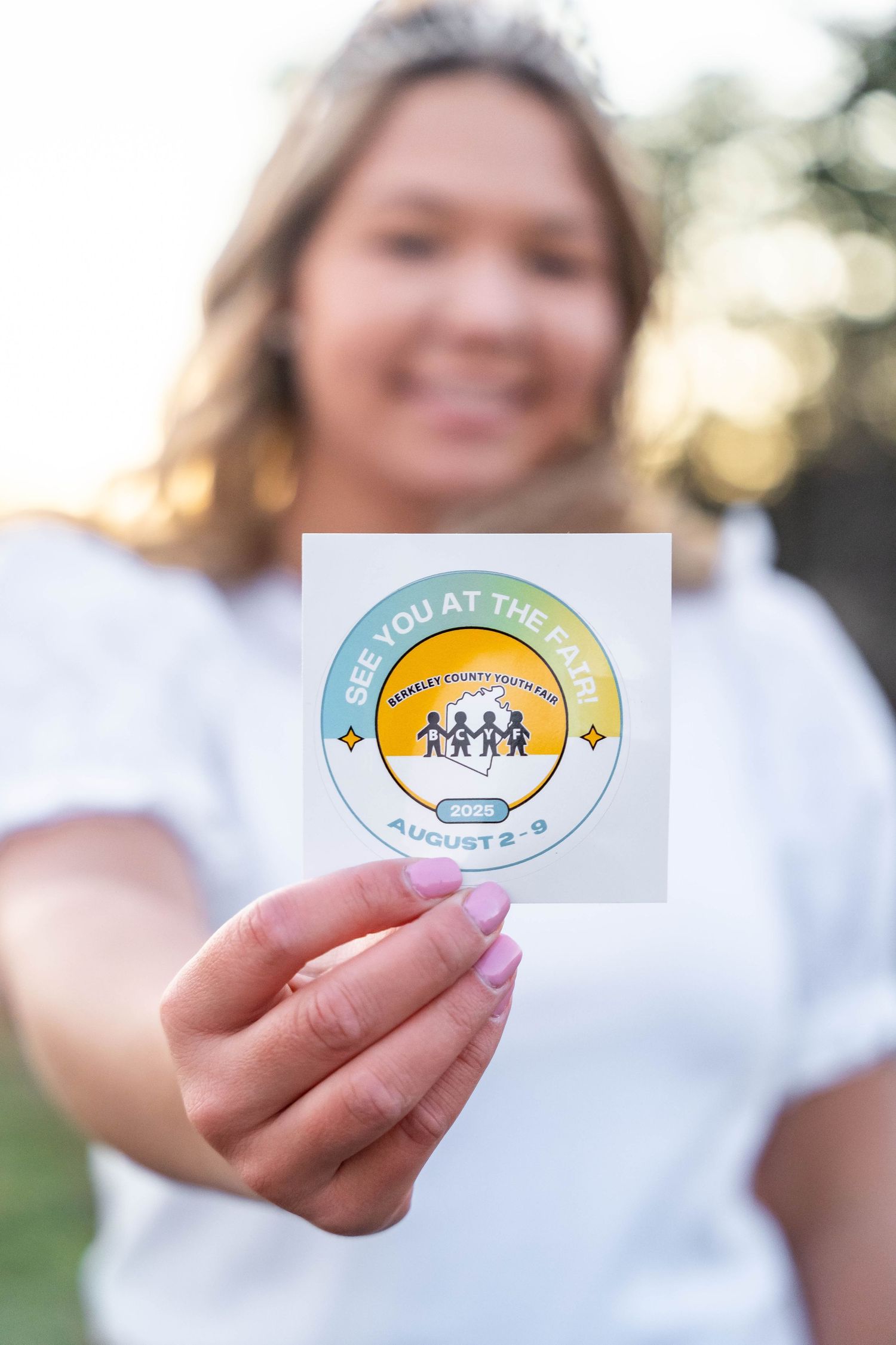 Three stickers being held up showing community and family-themed designs in white and teal colors.