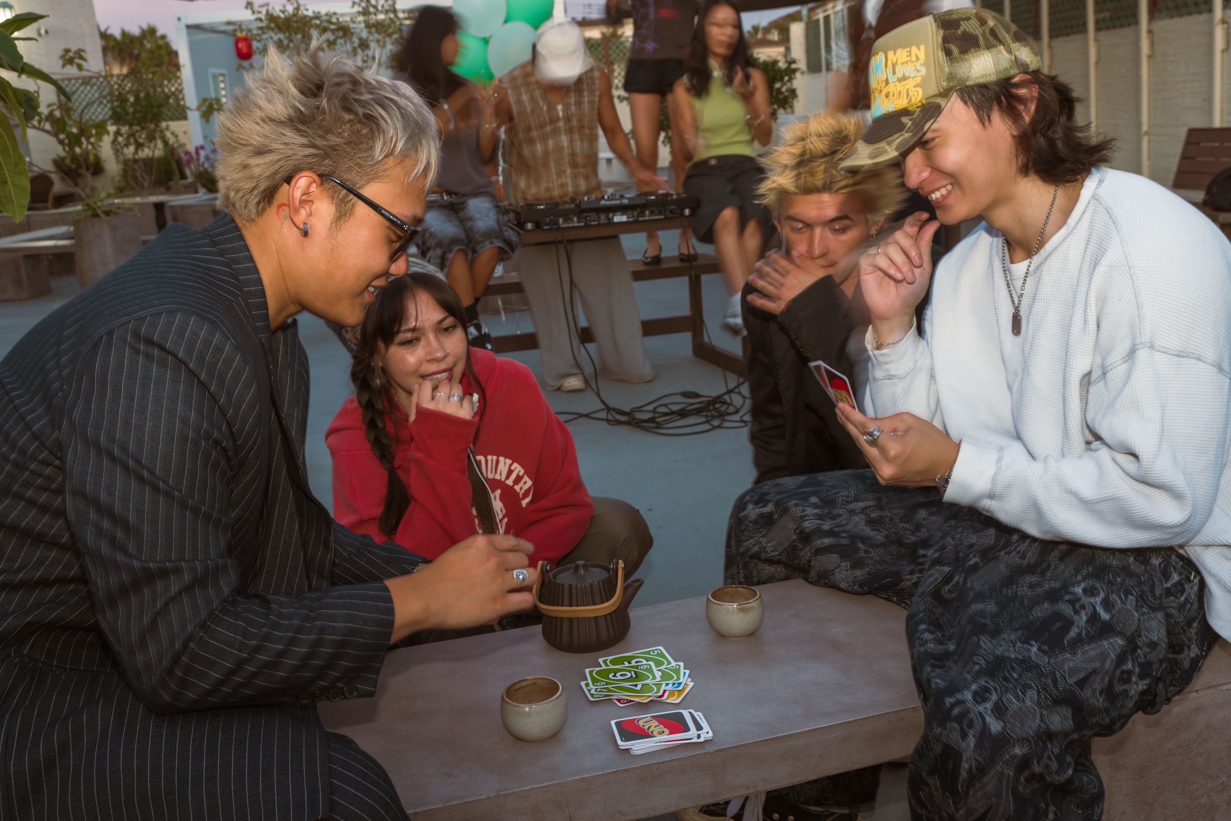 A group of friends gathered around a table playing cards during a casual social gathering.