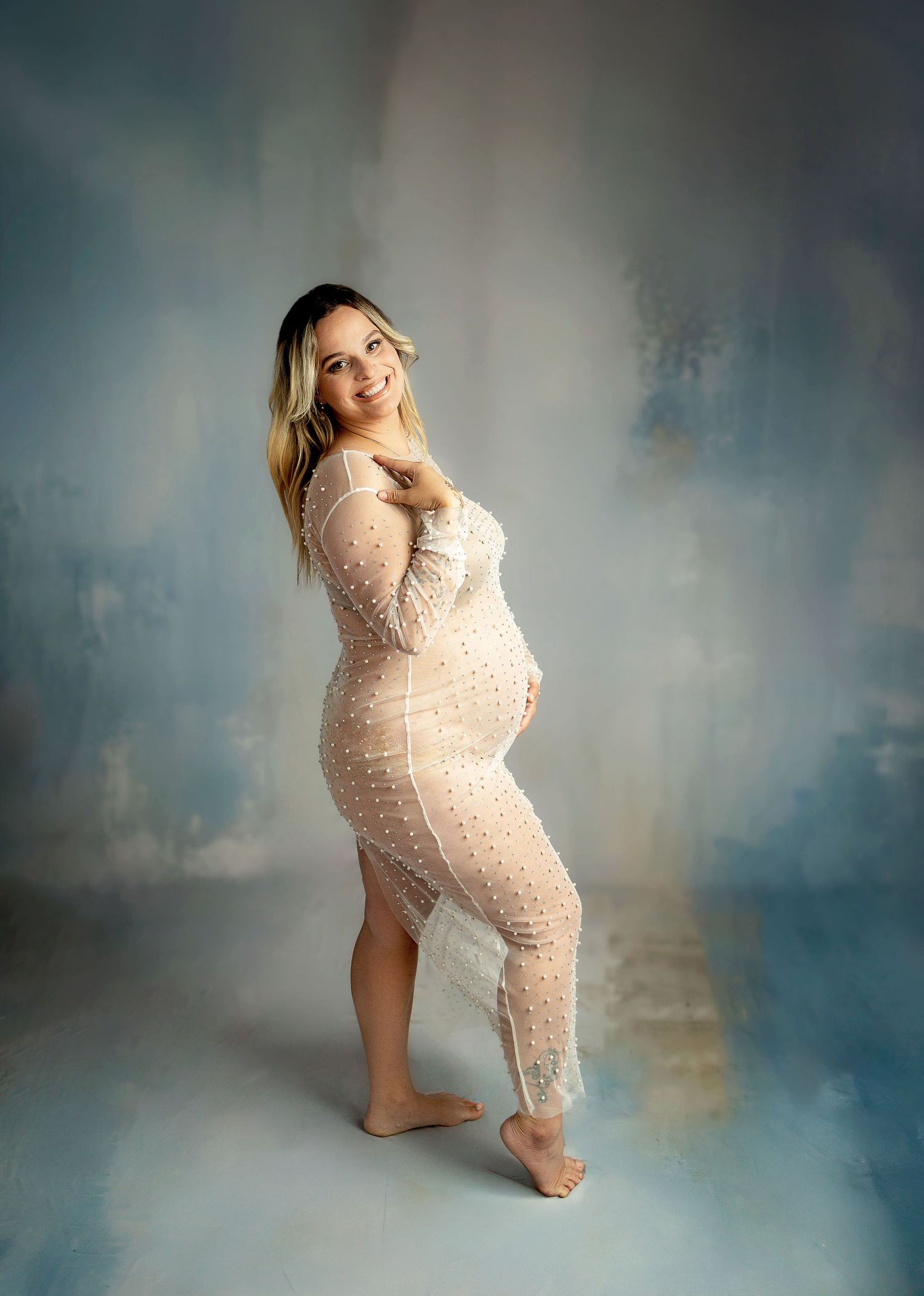 Four artistic black and white maternity photos show an expectant person in various poses wearing black clothing against a light backdrop.