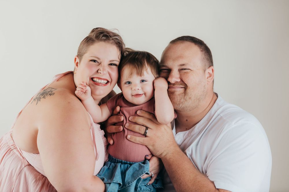 A family shares joyful laughter together during an intimate indoor portrait session.