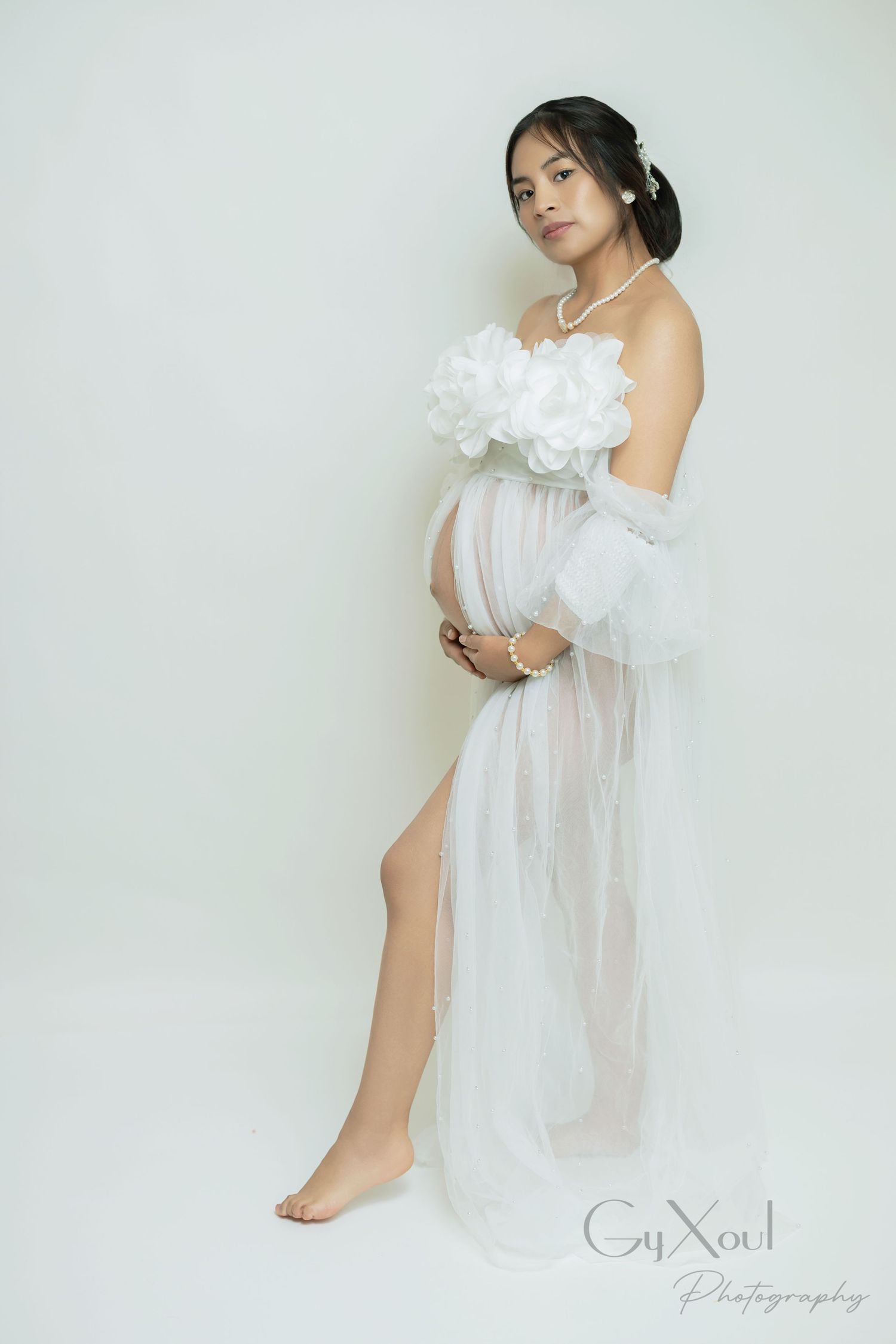 Black and white maternity photos show a woman in sheer fabric poses against a light background for studio portraits.
