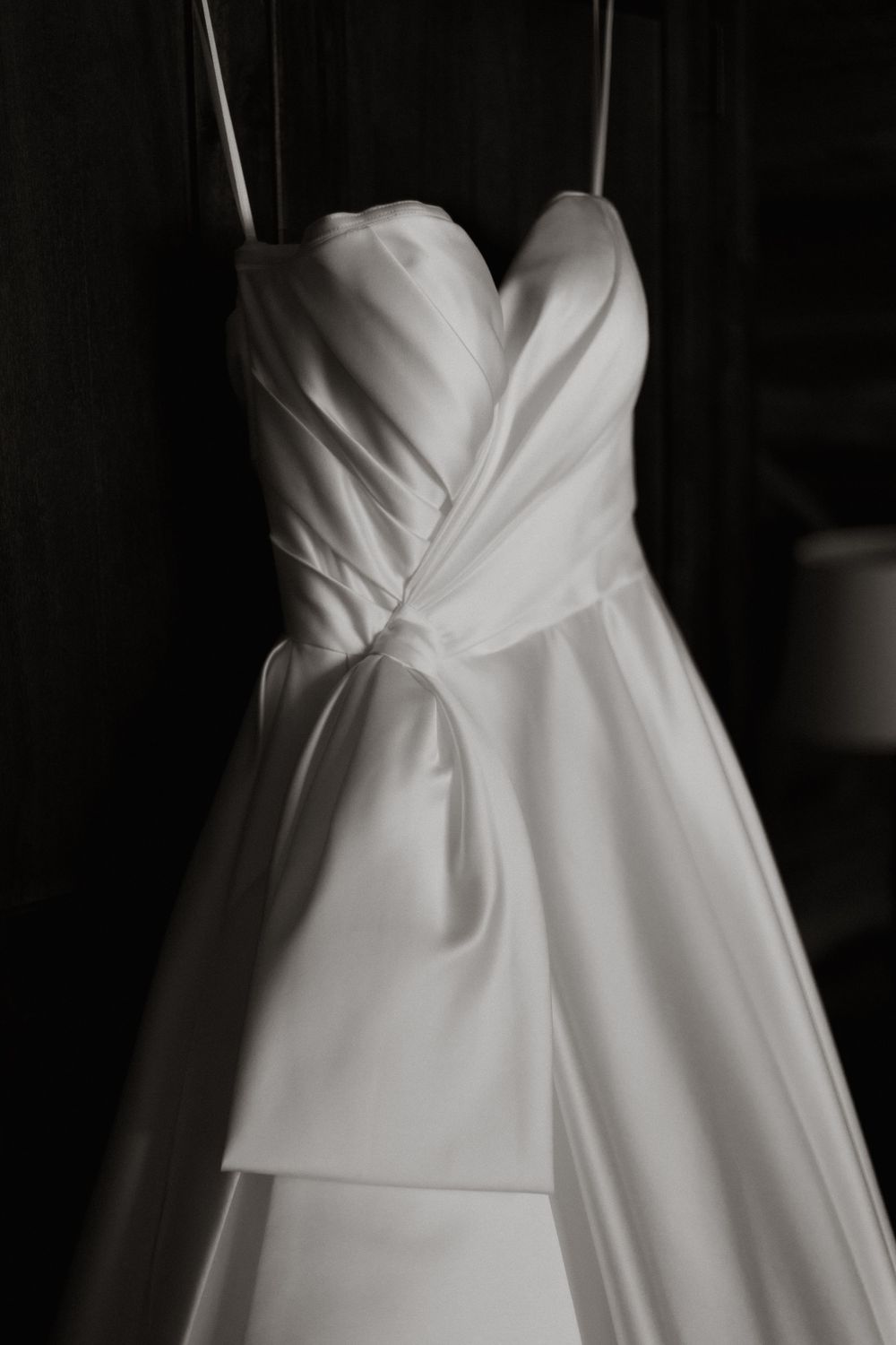 Close-up details of white wedding dresses showing pleating, draping and sweetheart necklines on hanging gowns.