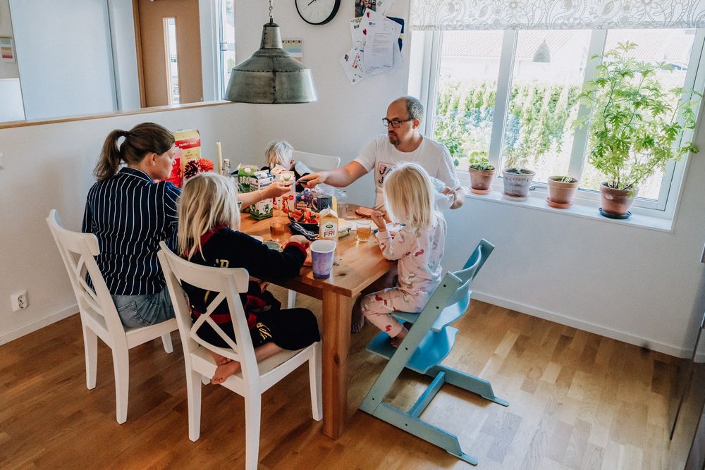 Familjen sitter vid köksbordet och äter frukost.
