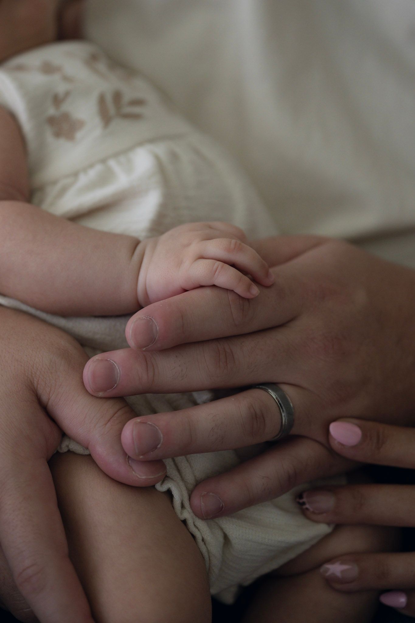 Close-up shots of intertwined hands resting on white bedding.