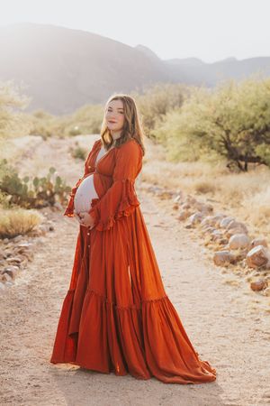A rust-colored tiered dress catches the desert breeze against a mountainous backdrop.
