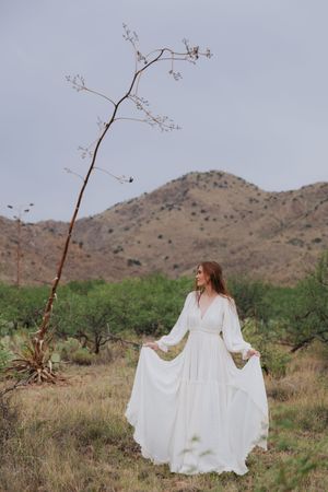 A flowing white dress moves gracefully in the desert landscape with mountains in the background.