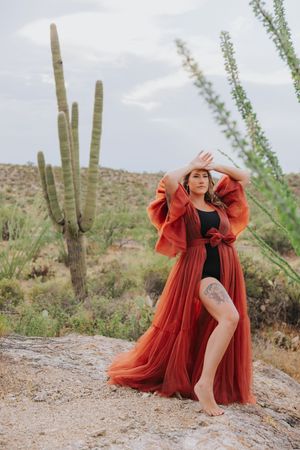 A dramatic red dress creates movement against desert cacti and mountains.